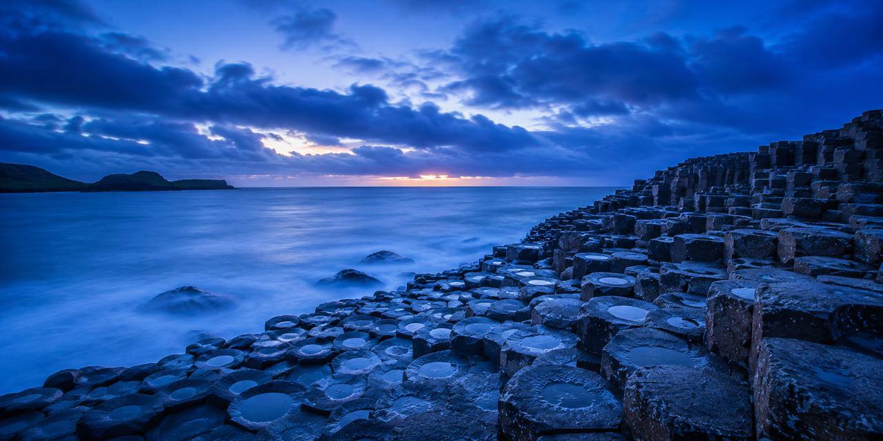 Blue hour coastal basalt rocks at the water's edge